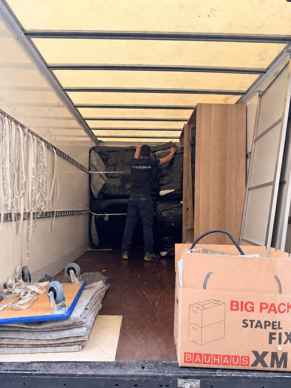 Umzugshelfer sichert geschützte Möbel sorgfältig im Transporter