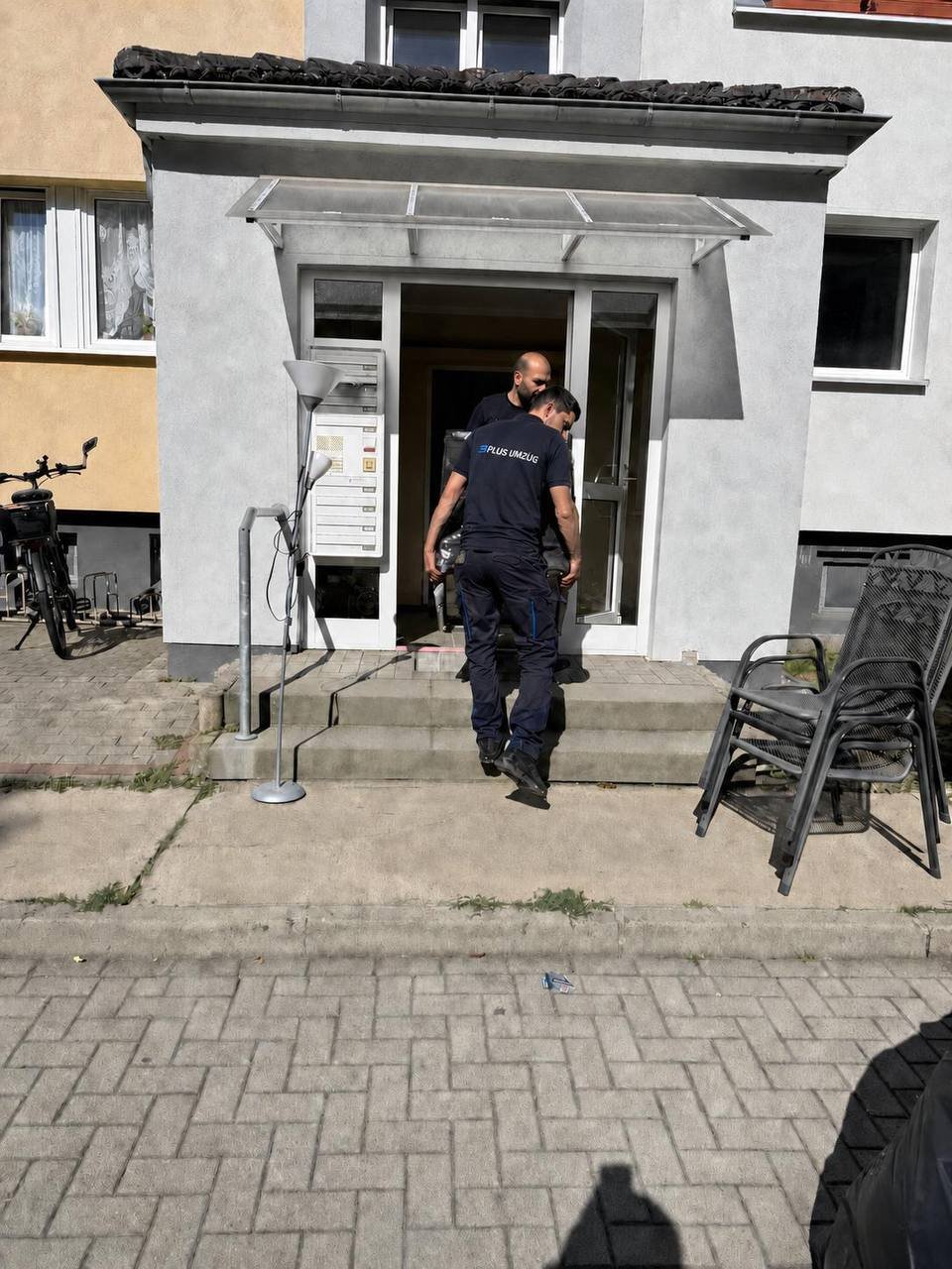 Zwei Umzugshelfer tragen ein Möbelstück sicher aus einem Hauseingang